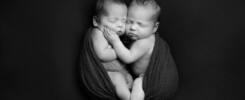 Black and white image of two newborns cuddling each other.
