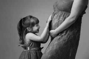 Little girl touching her mum's bump in black and white