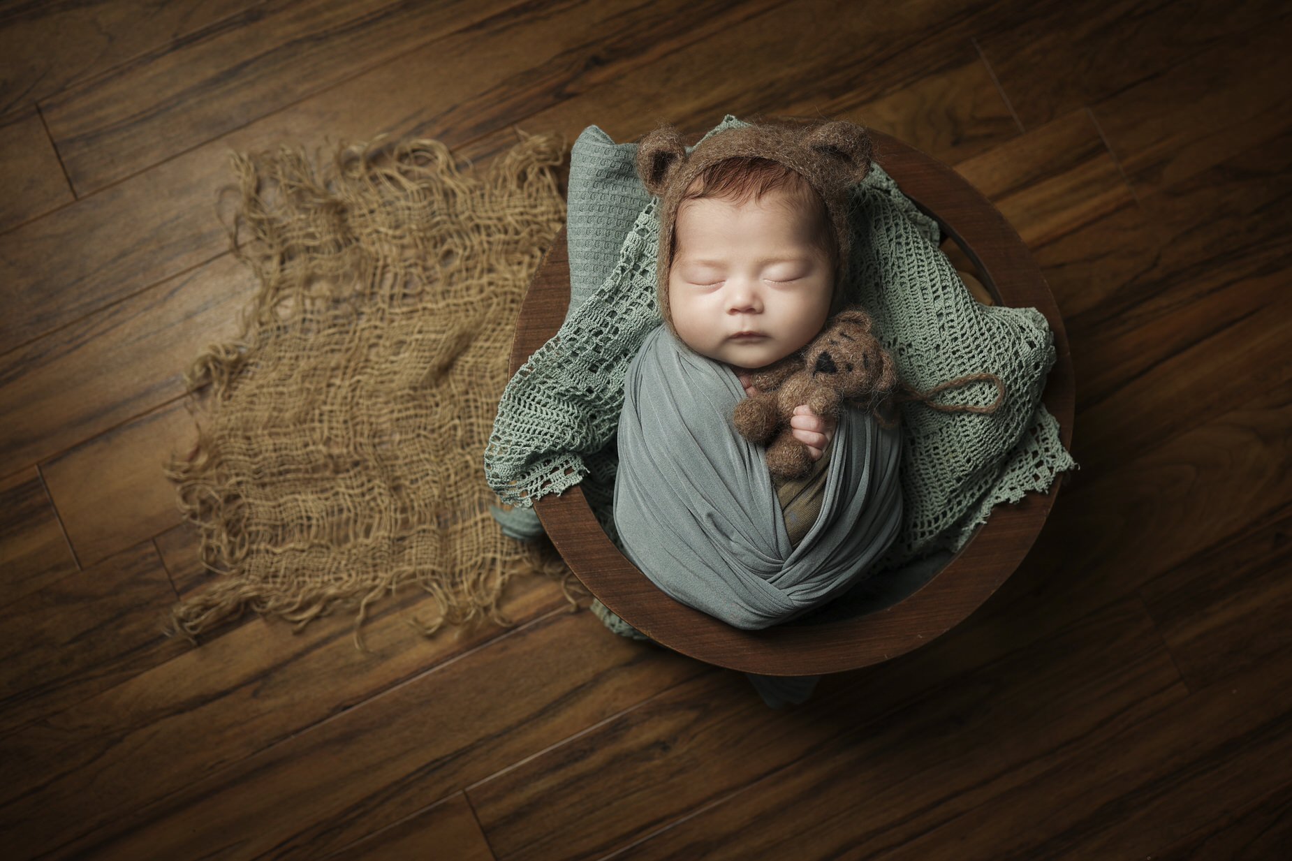 newborn asleep in basket all wrapped up cozy looking from above.