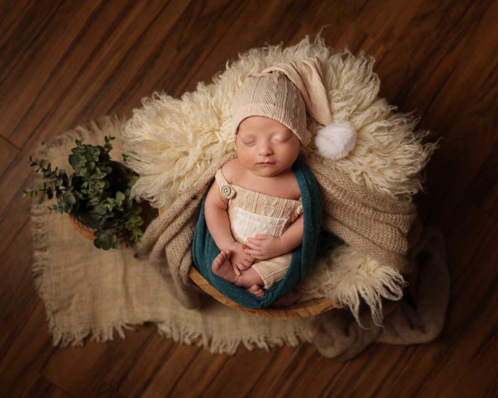 Sleeping Newborn in a basket on a wooden floor professional photography